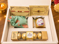 Rakhi Hamper with 2 Happy Rakshabandhan Rakhi cards, Meena Craft Store honey jar, green fabric dry fruit potli and Ferrero Rocher chocolates in a white branded gift box