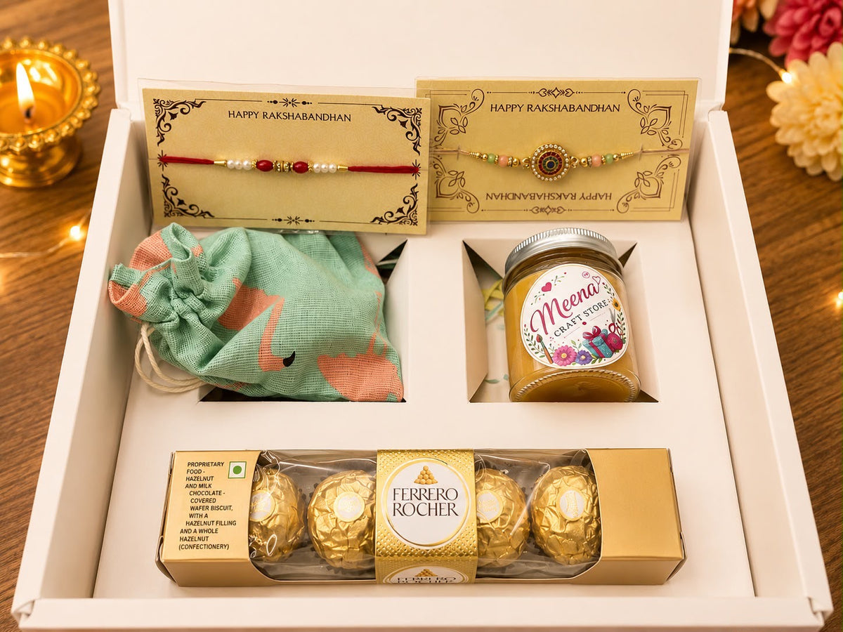 Rakhi Hamper with 2 Happy Rakshabandhan Rakhi cards, Meena Craft Store honey jar, green fabric dry fruit potli and Ferrero Rocher chocolates in a white branded gift box