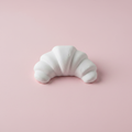 Croissant plaster fridge magnet figure on pink background