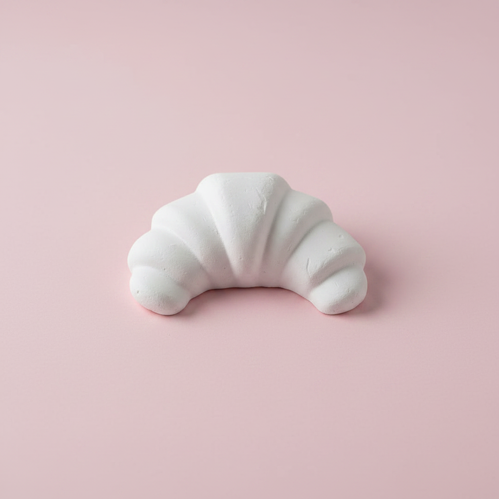 Croissant plaster fridge magnet figure on pink background