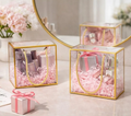 Square transparent golden border gift bags filled with cosmetics and pink shredded paper