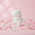Beautified product photo of unpainted white plaster T-Rex dinosaur figure on pastel pink background with flowers