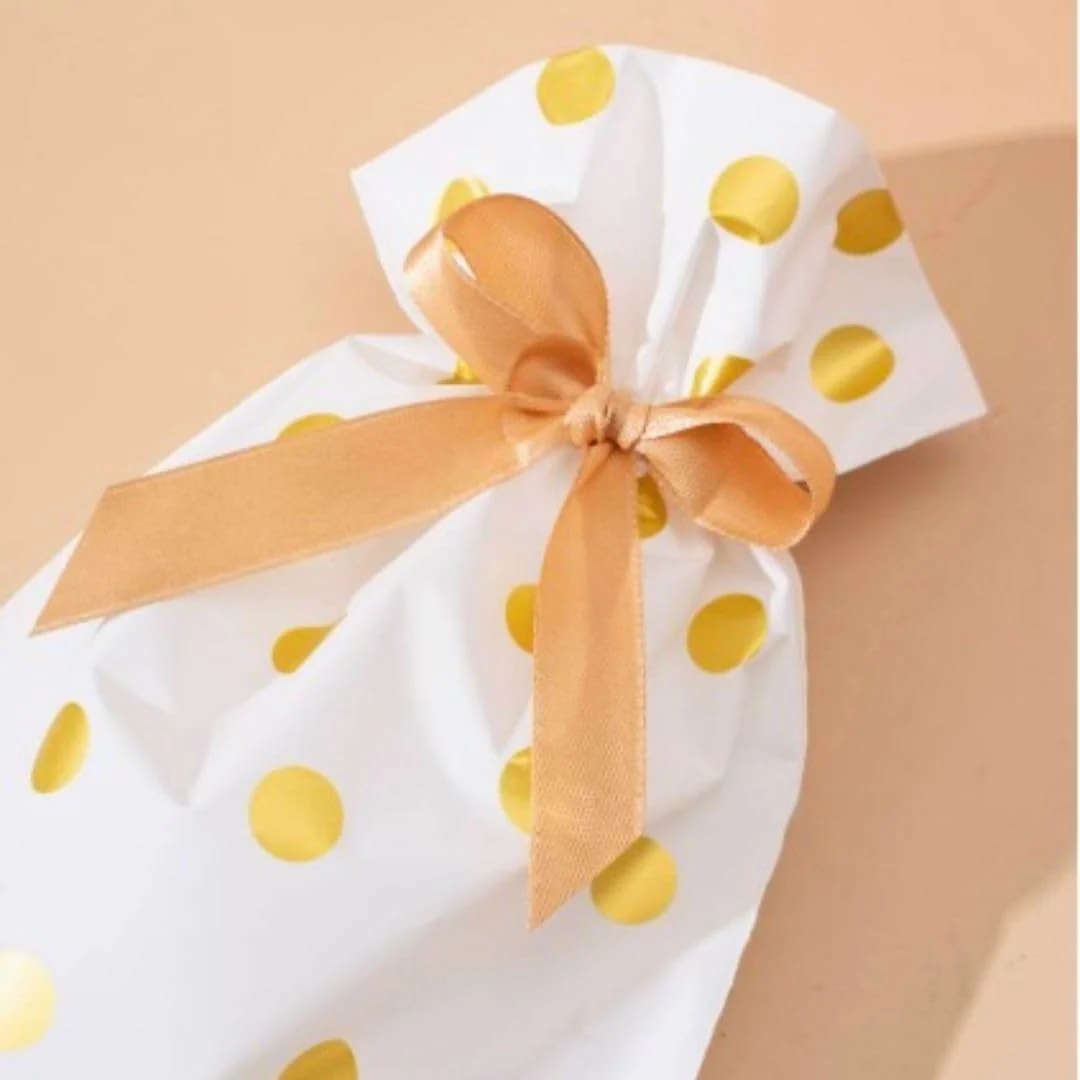 Close-up of white and gold polka dot gift pouch tied with gold satin ribbon bow