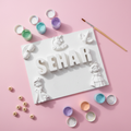Customisable kids name plaque with paint pots and brush flat lay