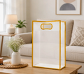 Large transparent golden border gift bag with die-cut handle in a living room setting