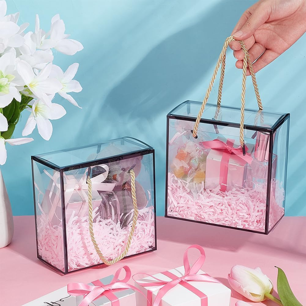 Two transparent black border gift bags with golden rope handles filled with gifts and pink shredded paper