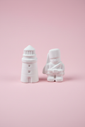 White unpainted plaster lighthouse and soldier figures on pastel pink surface