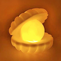 Pearl shell night lamp glowing warm golden yellow on orange background