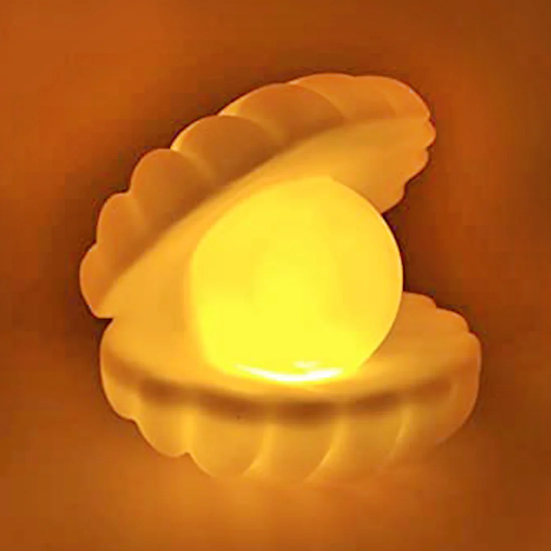 Pearl shell night lamp glowing warm golden yellow on orange background